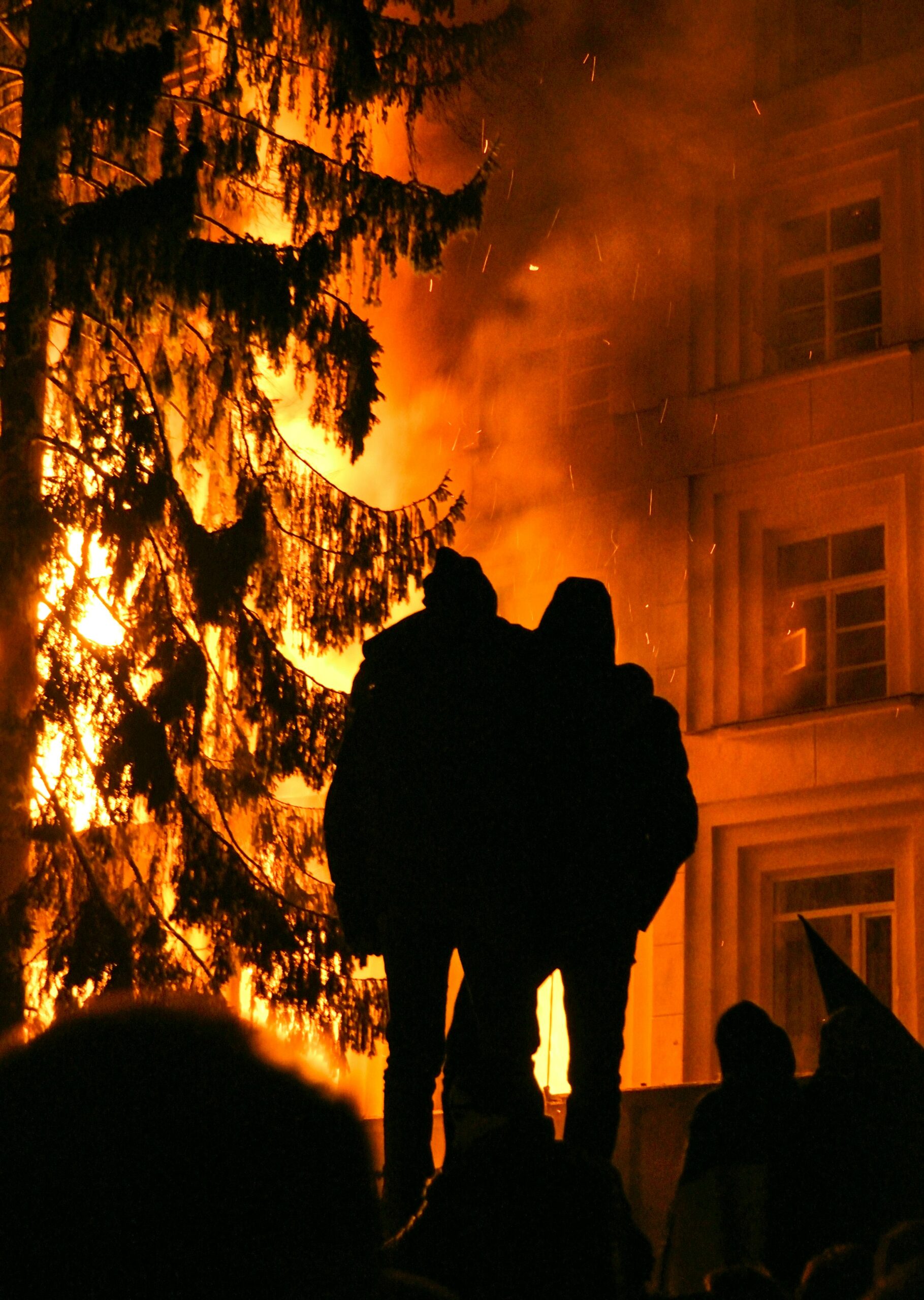 Servicios Silhouette of firefighters against flames engulfing a building at night in Lviv.